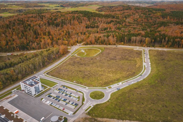 Aerial view of a roundel with surrounding buildings and autumn trees, new Lindenrain industrial park, Calw, Black Forest, Germany