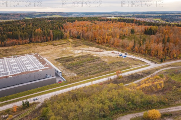 Landscape with road and autumn forests next to an industrial building, new Lindenrain industrial park, Calw, Black Forest, Germany