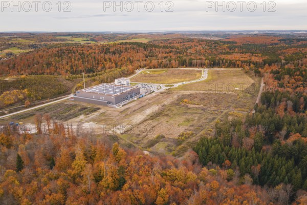 Industrial plant surrounded by autumnal forest with fields and roads in the background, new Lindenrain industrial park, Calw, Black Forest, Germany