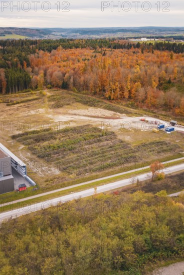 Construction site next to autumnal forest with visible earthworks and scattered trees, new Lindenrain industrial park, Calw, Black Forest, Germany