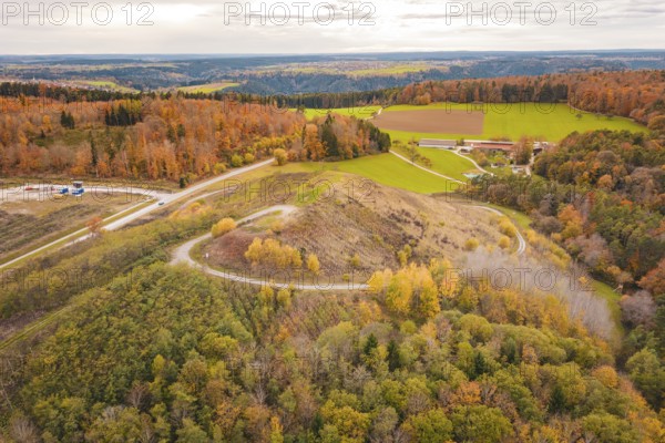 Hilly landscape with autumnal forests and open fields under cloudy sky, new Lindenrain industrial park, Calw, Black Forest, Germany