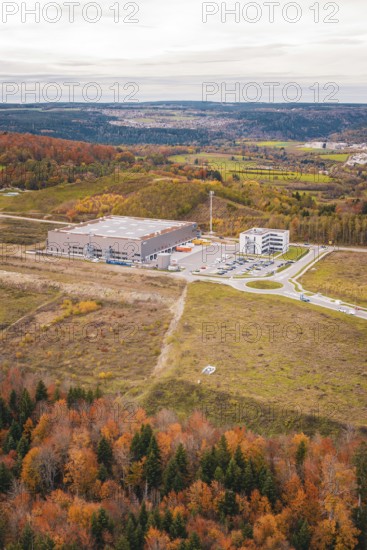 Large warehouse in the middle of a hilly landscape with autumn trees, new Lindenrain industrial park, Calw, Black Forest, Germany