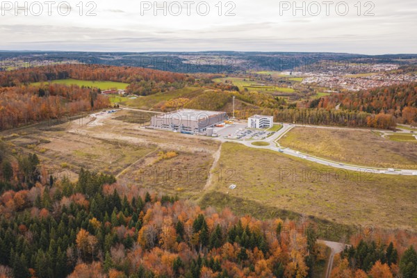 Hilly landscape in autumn with modern building and surrounding forest, new Lindenrain industrial park, Calw, Black Forest, Germany