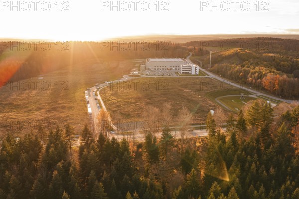 Scene at sunset with a building in the middle of a wooded landscape under soft light, new Lindenrain industrial park, Calw, Black Forest, Germany