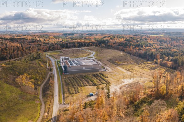 Aerial view of a building surrounded by an autumn forest landscape with dramatic sky, new Lindenrain industrial park, Calw, Black Forest, Germany