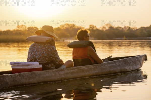 Sunset boat trip, tourists in a Mokoro, dugout boat on the Okavango River, Caprivi Strip, Namibia