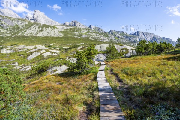 Wooden plank trail through mountain moor, in front of picturesque mountain landscape, Göscheneralp, Canton of Uri, Switzerland