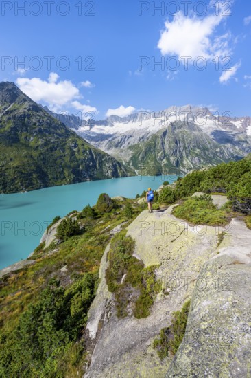 Female mountaineer in front of picturesque mountain landscape, turquoise-blue mountain lake Göscheneralpsee, Dammastock and Damma glacier, Göscheneralp, Canton of Uri, Switzerland