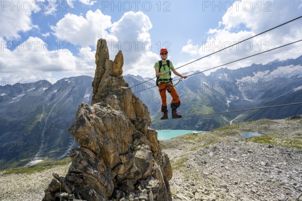 Crocodile rock formation, mountaineer on rope bridge in the Crocodile Mountain Lake via ferrata on Bergseeschijen-Vorbau, Göscheneralp, Canton of Uri, Switzerland