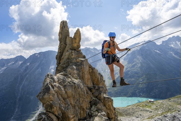 Crocodile rock formation, mountaineer on rope bridge in the Crocodile Mountain Lake via ferrata on Bergseeschijen-Vorbau, Göscheneralp, Canton of Uri, Switzerland