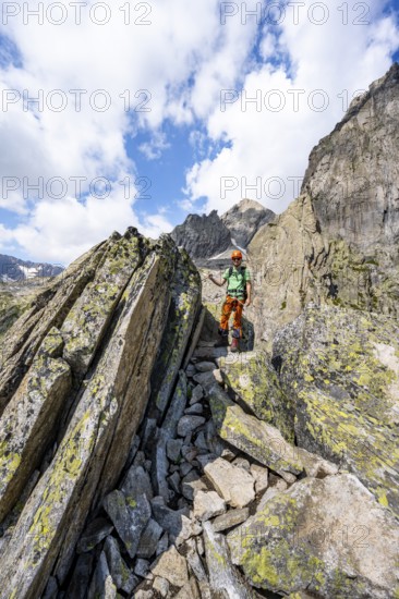 Mountaineers between boulders on the secured via ferrata Crocodile Mountain Lake at Bergseeschijen-Vorbau, Göscheneralp, Canton of Uri, Switzerland
