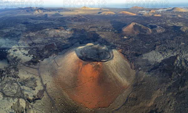 Caldera Colorada volcano, picturesque volcanic landscape with volcanic craters and lava fields in morning light, Parque Natural de Los Volcanes, aerial view, Lanzarote, Canary Islands, Spain
