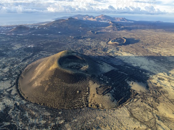 Montaña Negra volcano, picturesque volcanic landscape with volcanic craters and lava fields in morning light, Parque Natural de Los Volcanes, aerial view, Lanzarote, Canary Islands, Spain