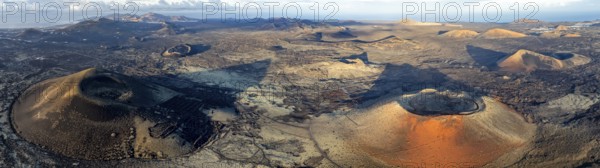 Caldera Colorada volcano and Montaña Negra, picturesque volcanic landscape with volcanic craters and lava fields in morning light, Parque Natural de Los Volcanes, aerial view, Lanzarote, Canary Islands, Spain