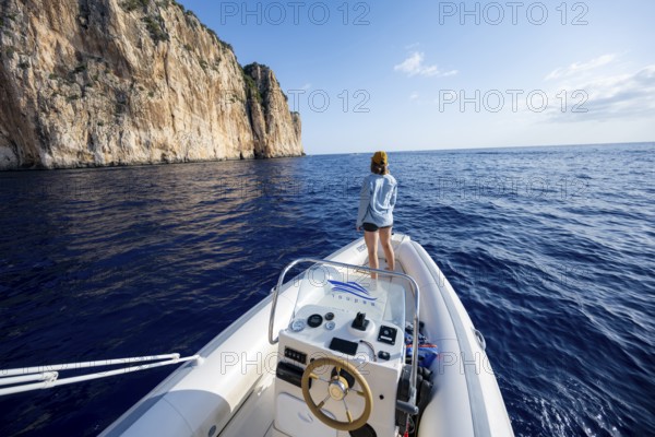 Young woman enjoying the countryside, motorboat ride along the picturesque rocky coast, cliffs and blue sea, Golfo di Orosei, Baunei, Sardinia, Italy