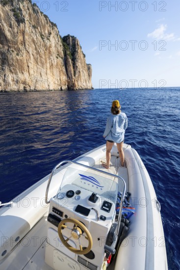 Young woman enjoying the countryside, motorboat ride along the picturesque rocky coast, cliffs and blue sea, Golfo di Orosei, Baunei, Sardinia, Italy