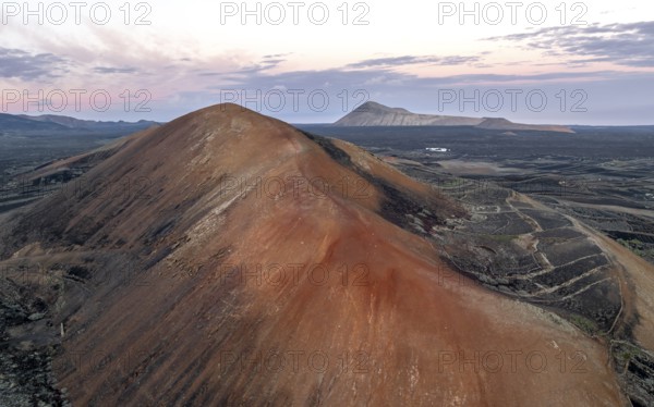 Red volcano Montaña Corujo, picturesque volcanic landscape with volcanic craters at sunrise, Parque Natural de Los Volcanes, aerial view, Lanzarote, Canary Islands, Spain