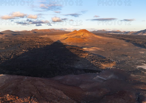 Picturesque volcanic landscape in evening light, Montaña Bermeja volcano between lava fields, aerial view, Lanzarote, Canary Islands, Spain