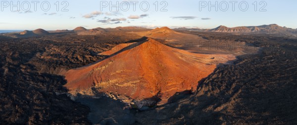 Volcanic landscape in evening light, red volcano Montaña Bermeja between lava fields, aerial view, Lanzarote, Canary Islands, Spain