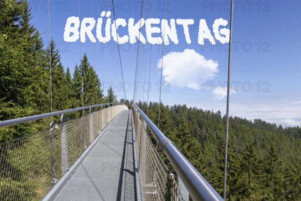 Bridge Day Symbolic image: Suspension bridge with font BRÜCKENTAG inserted in the sky (digitally edited)