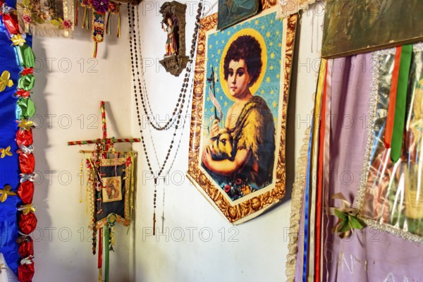 Religious objects on the wall of a simple and rustic house in the interior of Minas Gerais, Brazil with saints and entities from different religions