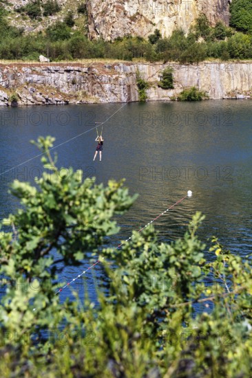 Tourist on a zip line across the lake, Opal Lake in the granite quarry, Moselleøkken Stenbrudsmuseum, museum in the quarry, Hammerknuden, Allinge-Sandvig, Bornholm, Denmark
