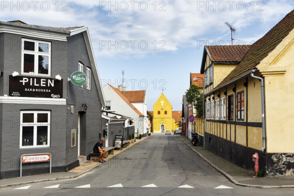 Street with bar and half-timbered houses, yellow church in Allinge, Treppengable, Allinge-Sandvig, Bornholm, Denmark