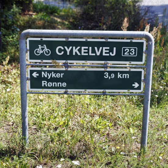 Danish sign with the inscription Radweg 23, distance to Nyker and Rønne, bicycle tour through coastal landscape, Bornholm, Denmark