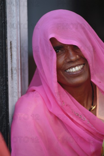 Smiling woman, face partly covered by long, scarf-like pink shawl or Dupatta, also known as Chunni, Chunari, Chundari, Bambora, Rajasthan, India