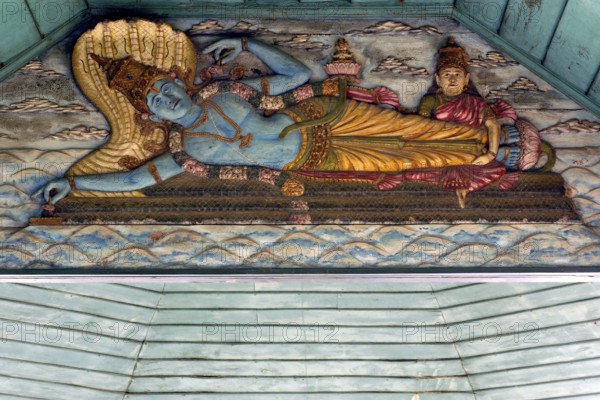 Painted wooden relief, Hindu god Vishnu on the snake Shesha in the primeval sea with wife Lakshmi massaging his feet as a gesture of worship, while from his navel, sitting on a lotus flower, appears the four-person creator Brahma, Kalari Kovilakom, Ayurveda Palace of the Cgh-Earth Hotel Group, Kollengode, Vengunad, Kerala, India
