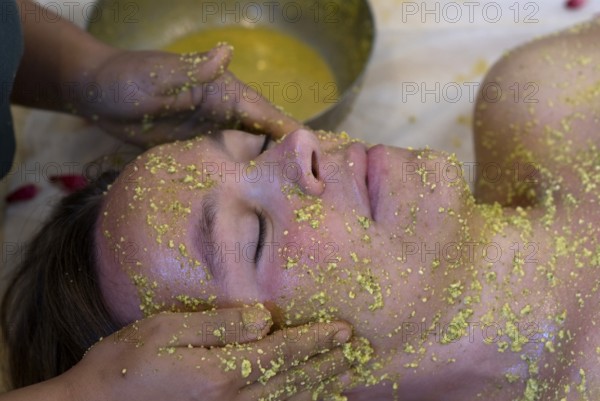 Person gets a relaxing facial massage with yellow Ayurvedic paste, Udaipur, Rajasthan, India