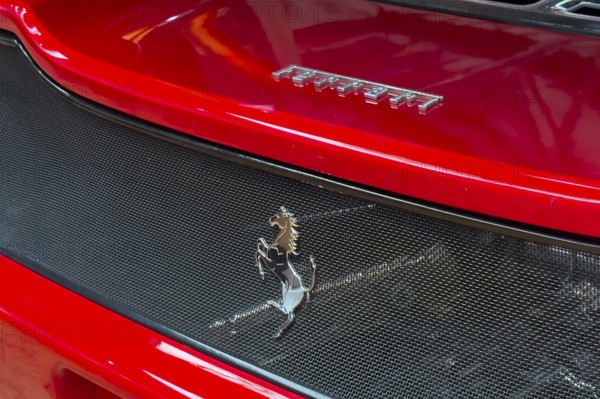 Close-up cutout detail part of red rear rear end of sports car Supercar Ferrari with logo trademark of luxury car manufacturer Jumping horse Cavallino Rampante, international