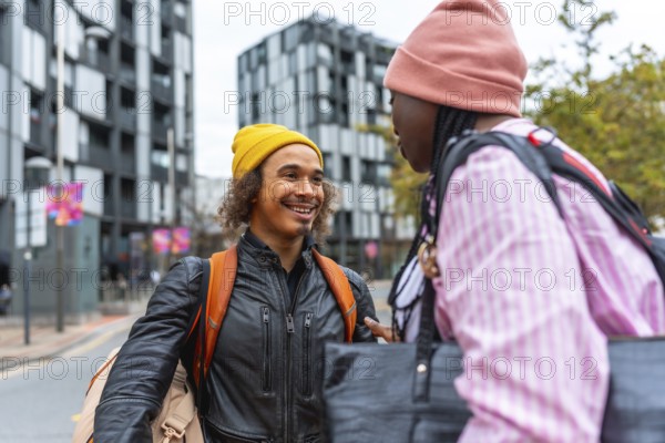 Young diverse friends smiling and chatting on a city street, casually dressed in street style, enjoying an urban hangout and friendly connection during a sunny day