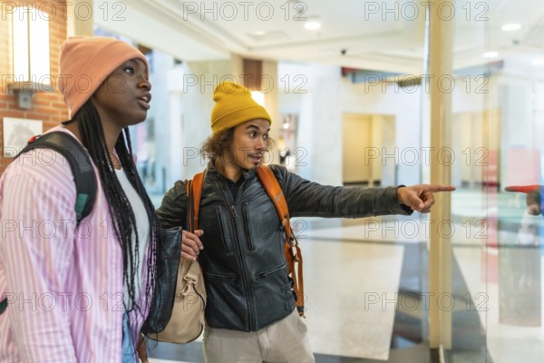Young friends window shopping in a bright modern mall, pointing at a boutique display through glass, sharing a casual moment of browsing, conversation and curiosity