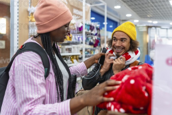 Diverse young couple shopping together in a store, smiling and trying on a neck pillow while browsing travel accessories and preparing for a fun trip or weekend getaway