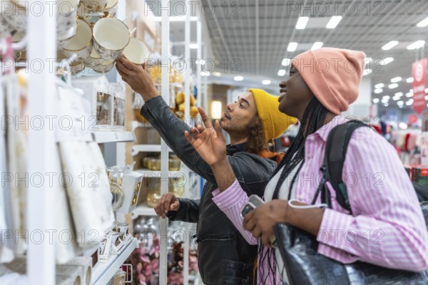 Mixed-race couple browsing colorful home decor and dinnerware on bright store shelves, smiling and enjoying a shared shopping experience while selecting mugs and kitchenware