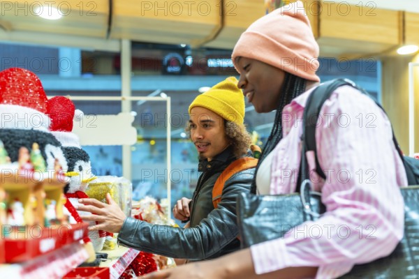 Young diverse couple shopping for holiday decorations, selecting gifts and enjoying their time together during the festive season inside a cheerful retail environment