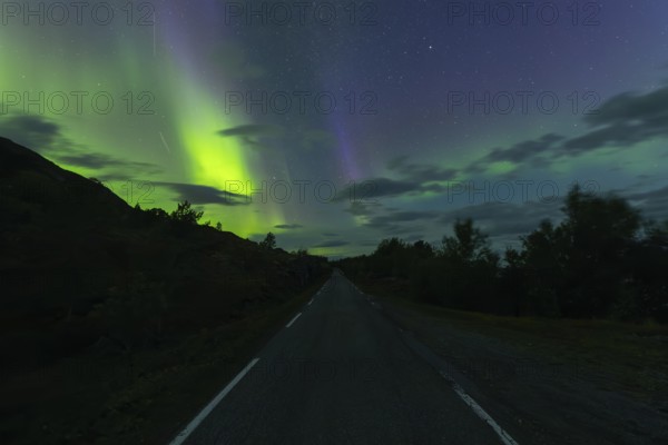 Road with northern lights at dawn at Sørfolda Fjord near Kjerringøy between Bodø and Sørfold in Norway
