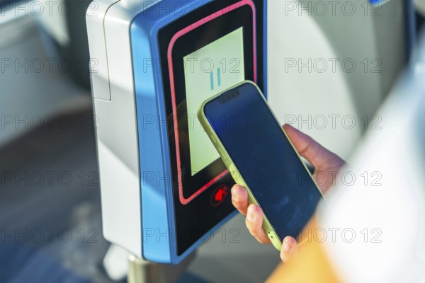 Person using mobile phone for contactless payment on a bus or public transport turnstile, highlighting modern digital transaction technology and urban travel convenience