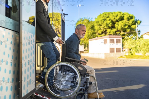 Caregiver assisting a smiling senior man using a wheelchair onto a public bus via an extendable ramp, demonstrating urban public transportation accessibility and daily support for disability