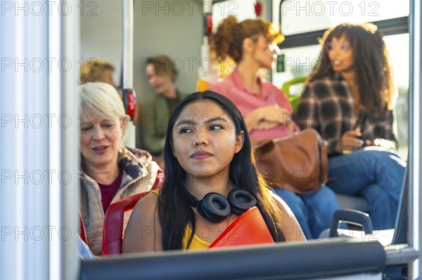 Young woman looking away while commuting on a bus with a diverse group of passengers, representing urban travel and daily life for people relying on public transportation