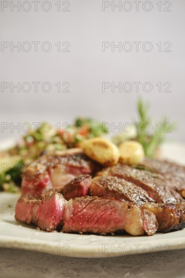 Juicy grilled steak medium rare on a white plate, with tender pink meat visible