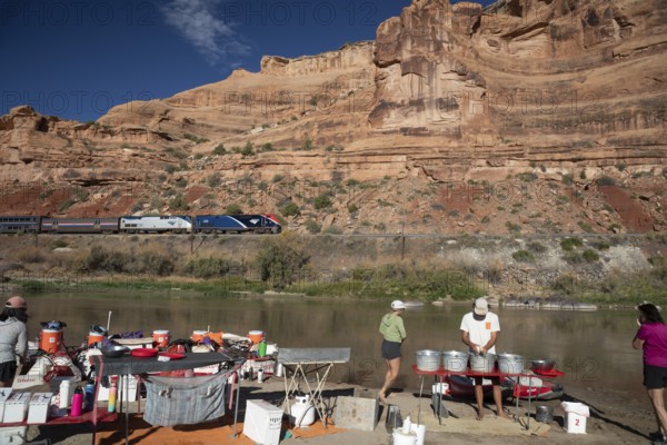 Loma, Colorado - Amtrak's California Zephyr passes a river rafters' campsite on the Colorado River in Ruby Canyon. The raft trip was run by Holiday River Expeditions