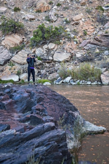 Cisco, Utah - A photographer stands on a rock by the Colorado River in Westwater Canyon