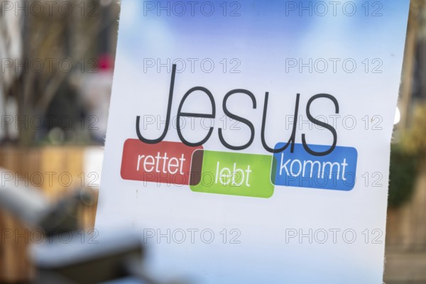 Sign with the inscription JESUS RETTET LEBT KOMMT at the information stand of a free church in downtown Speyer