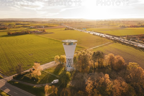 Water tower in autumn landscape with a wide view over fields and roads in the evening light, Möglingen water tower, Germany