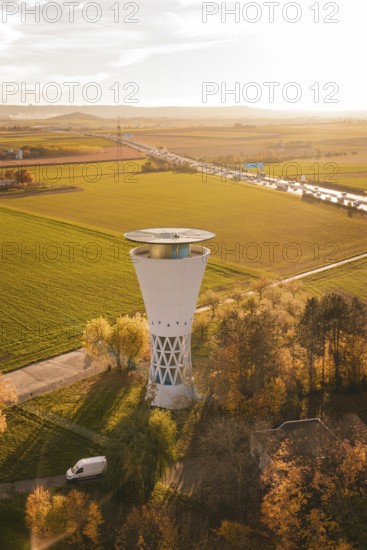 Water tower in autumn landscape surrounded by fields and trees at sunset, Möglingen water tower, Germany