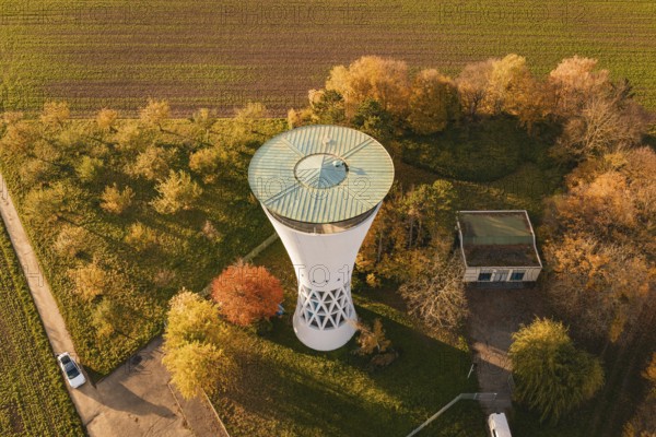 Autumn landscape with water tower and adjacent building, surrounded by nature, Möglingen water tower, Germany