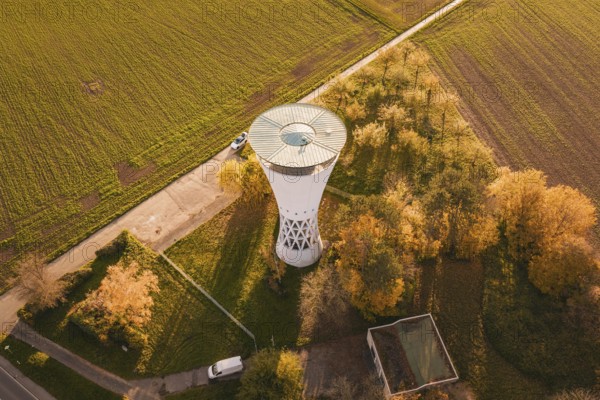 Water tower with surrounding autumn leaves, bordering fields in rural surroundings, Möglingen water tower, Germany