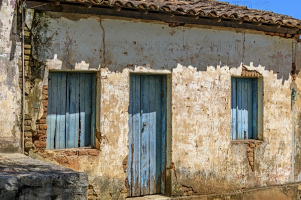 An old, abandoned house, ravaged by time, with its blue windows and crumbling plaster on the walls